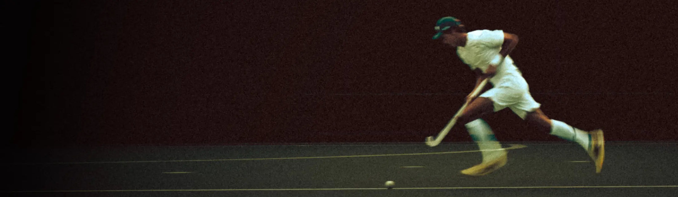 Hockeyer die over het veld rent. In wit tenue.